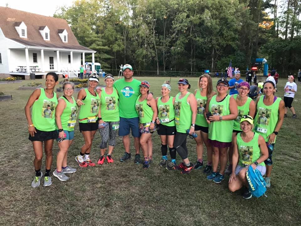 Group of women in green tank tops posing with Trent Swanson. 