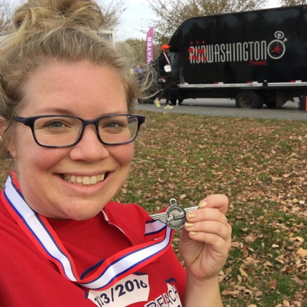 Vanessa Junkin poses with medal in front of RunWashington Timing truck. 