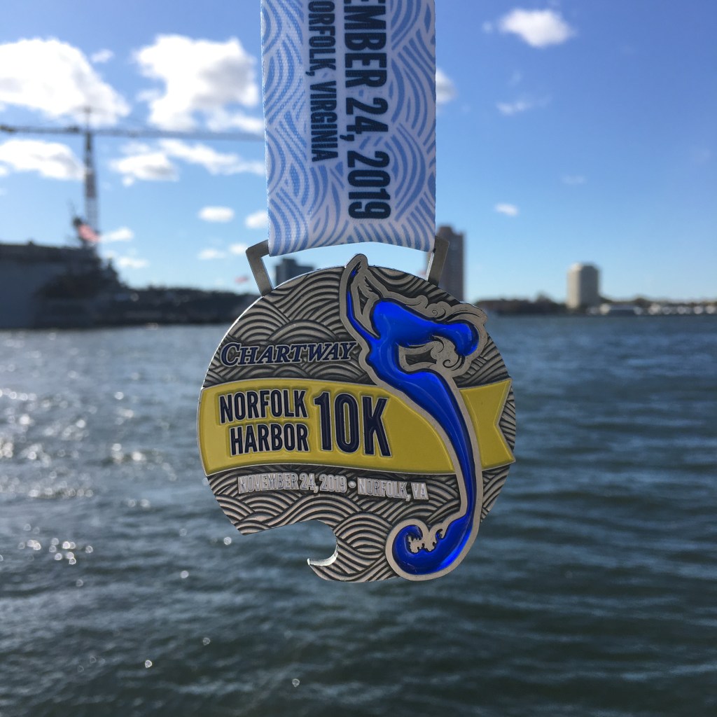 Norfolk Harbor 10K medal, shown with the light coming through a mermaid that is part of the medal.