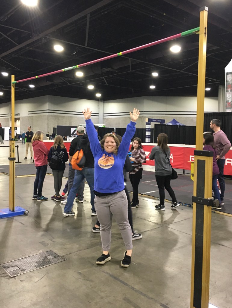 Vanessa Junkin poses under the high jump world record height with her arms up. 