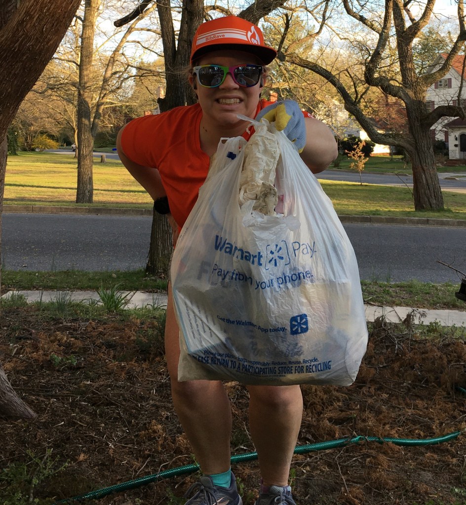 Vanessa Junkin holds out a grocery bag full of trash in front of her. 