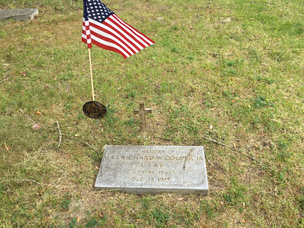 Marker with a small cross behind it and American flag near it. The marker reads: 
In Memory Of
Maj. Richard W. Cooper Jr. 
USAF
Nov 18 1942
Dec 19 1972