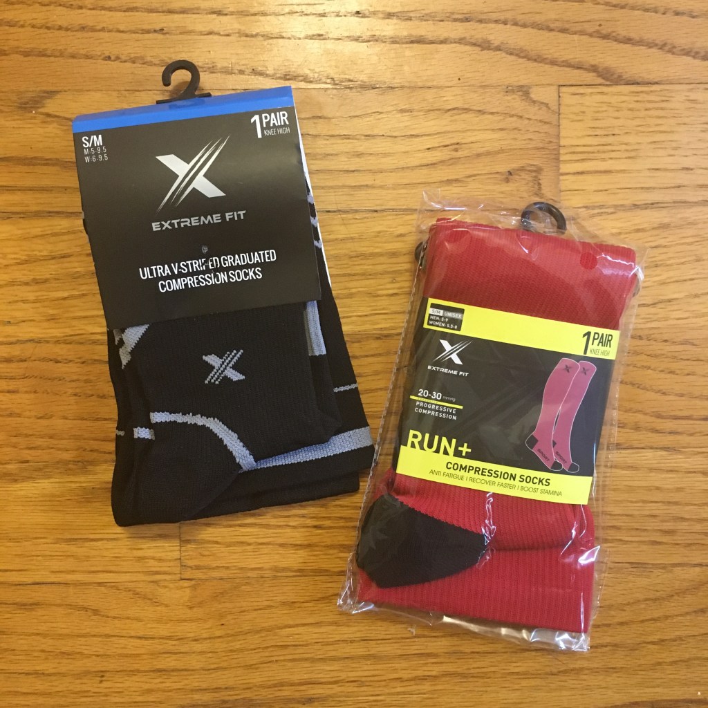 Two pairs of socks, one black and gray and one red, against a wood floor background. 