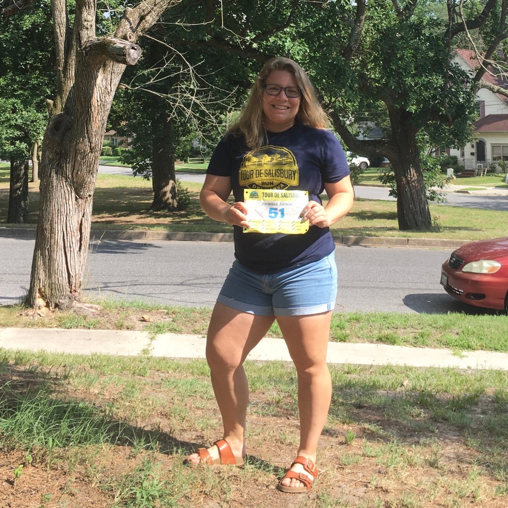 Vanessa Junkin poses in Tour de Salisbury shirt and holding the completed race bib. 
