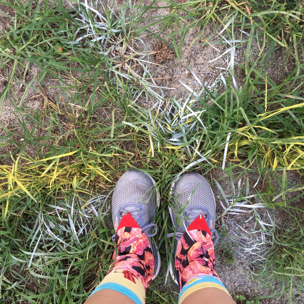 Running shoes with bacon gaiters standing on a white spray-painted X marked on a yellow spray-painted line.