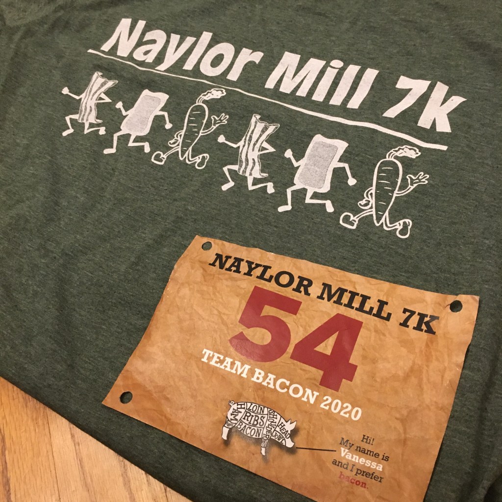 Green T-shirt that says "Naylor Mill 7K" and has running bacon, scrapple and veggies on it, with the brown race bib on top. 