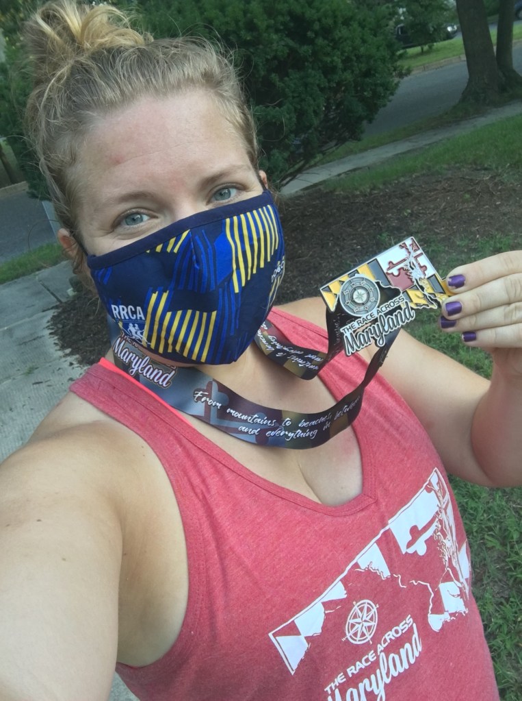 Selfie of Vanessa Junkin wearing mask and holding Race Across Maryland medal, wearing Race Across Maryland tank top. 