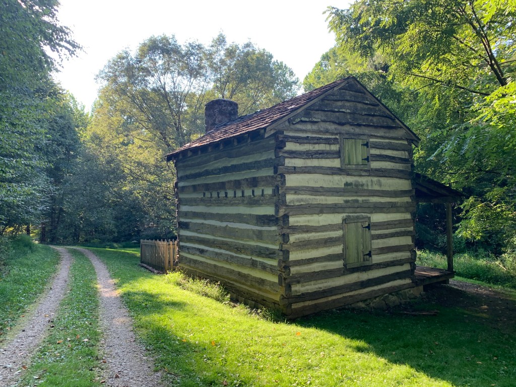 Historic cabin shown with trail on the left. 