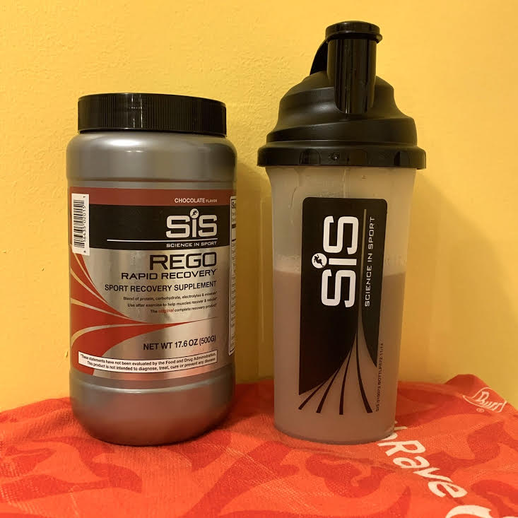 Canister of Science in Sport REGO Rapid Recovery next to a Science in Sport bottle showing the mixed chocolate drink.
