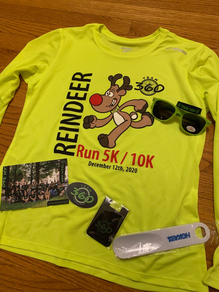 Reindeer Run long-sleeve tech shirt with various swag items around it (sunglasses, postcard, bracelet, sticker, etc.)
