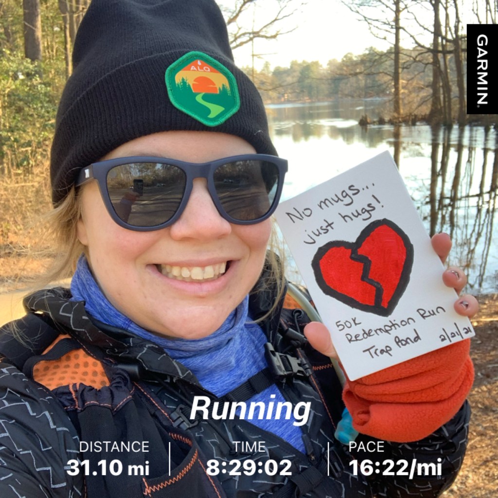 Selfie of female runner in winter hat and sunglasses holding rectangular finisher award with broken heart on it. Text reads "Running," "Distance: 31.10 mi," "Time 8:29:02," and "Pace 16:22/mi."