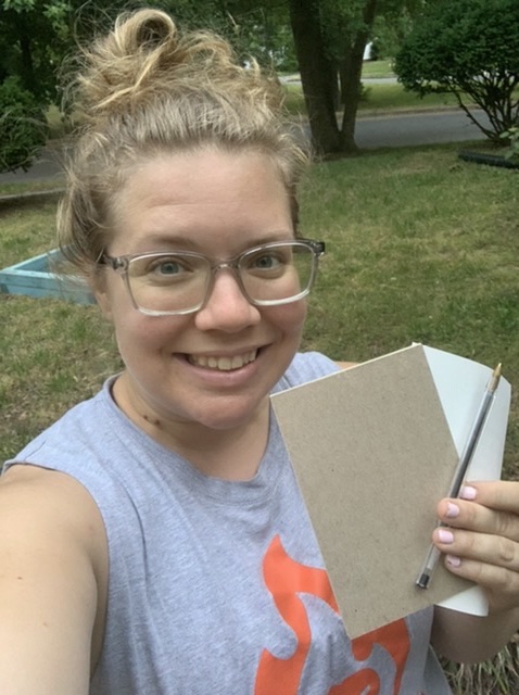 Selfie of Vanessa Junkin holding a notepad and pen. 