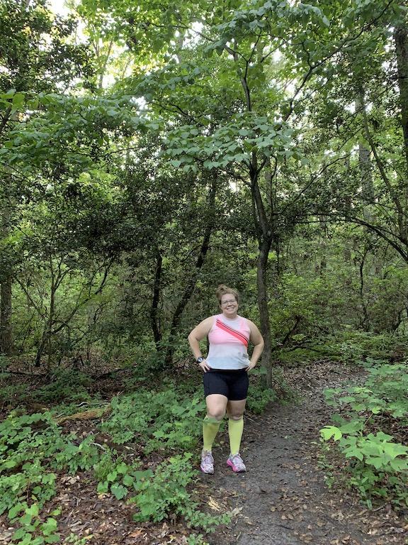 Vanessa Junkin posing in running clothes in the forest. 