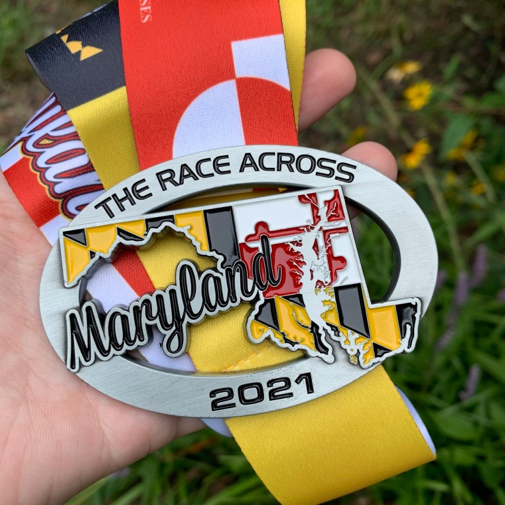 Close-up photo of Race Across Maryland medal, which has the state on it with the state flag pattern in the state.