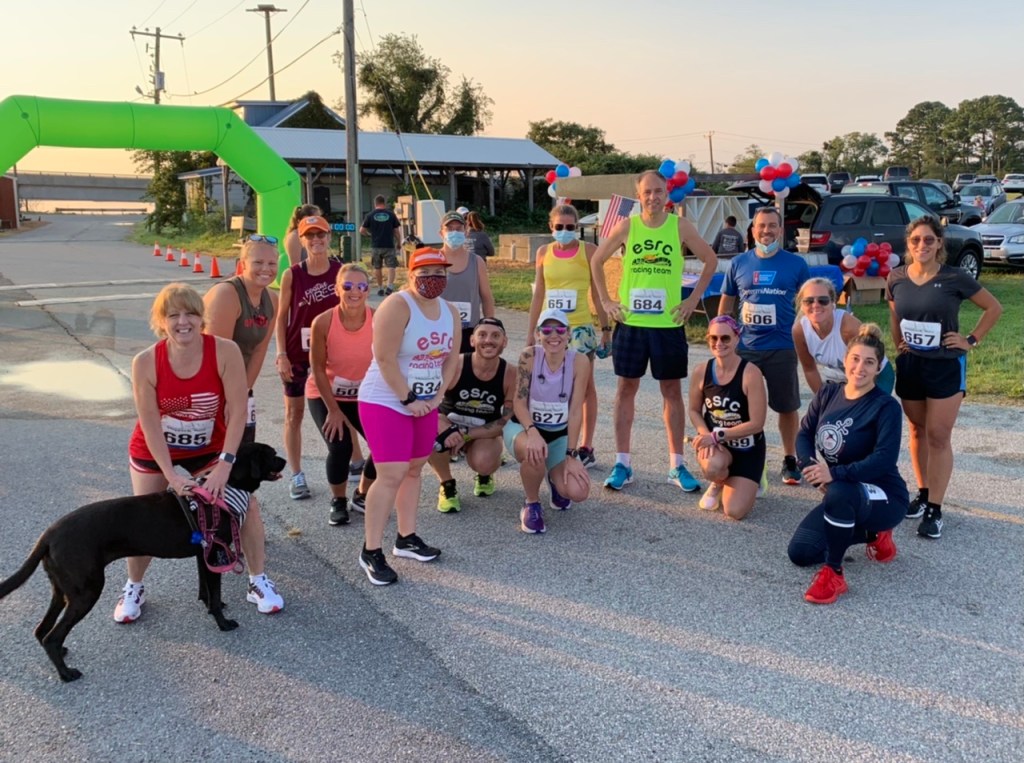 Group of runners poses for a photo near green race arch.