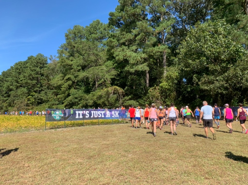 Participants start a 5K during the Pemberton 24. A banner says "It's Just a 5K." 