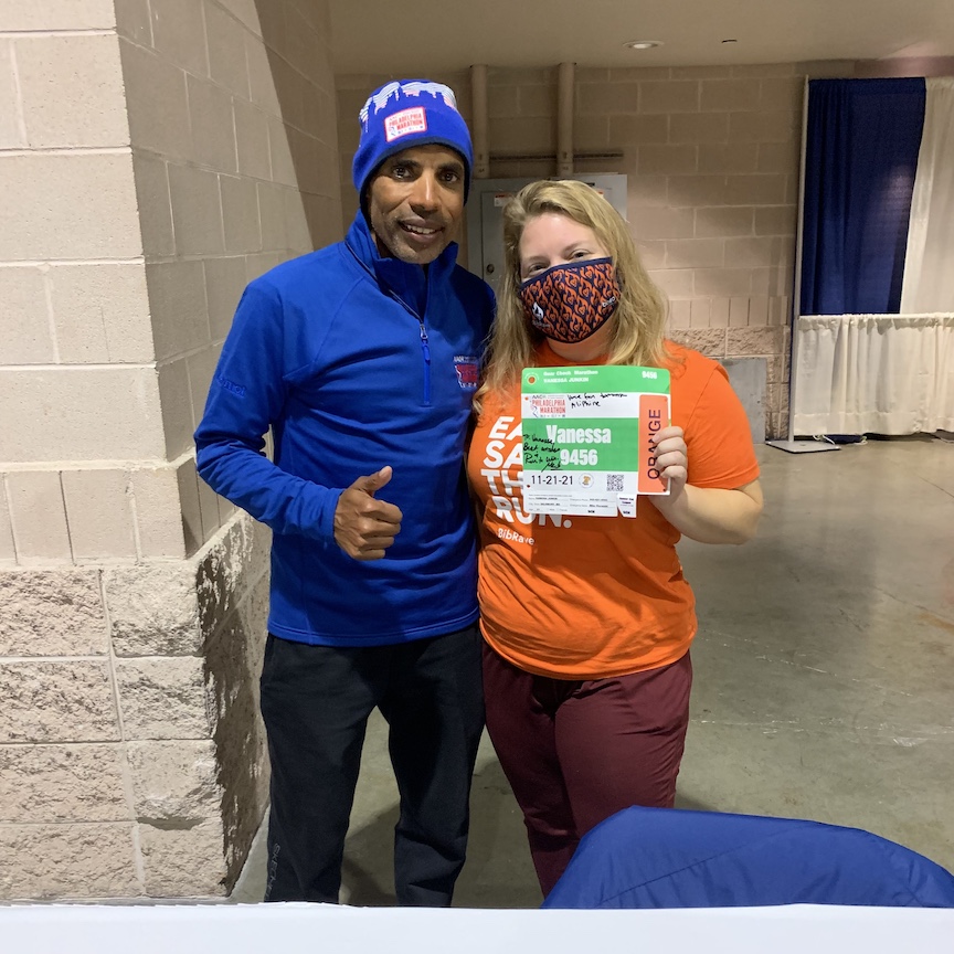 Meb Keflezighi and Vanessa Junkin pose for a photo. Vanessa is holding race bib.