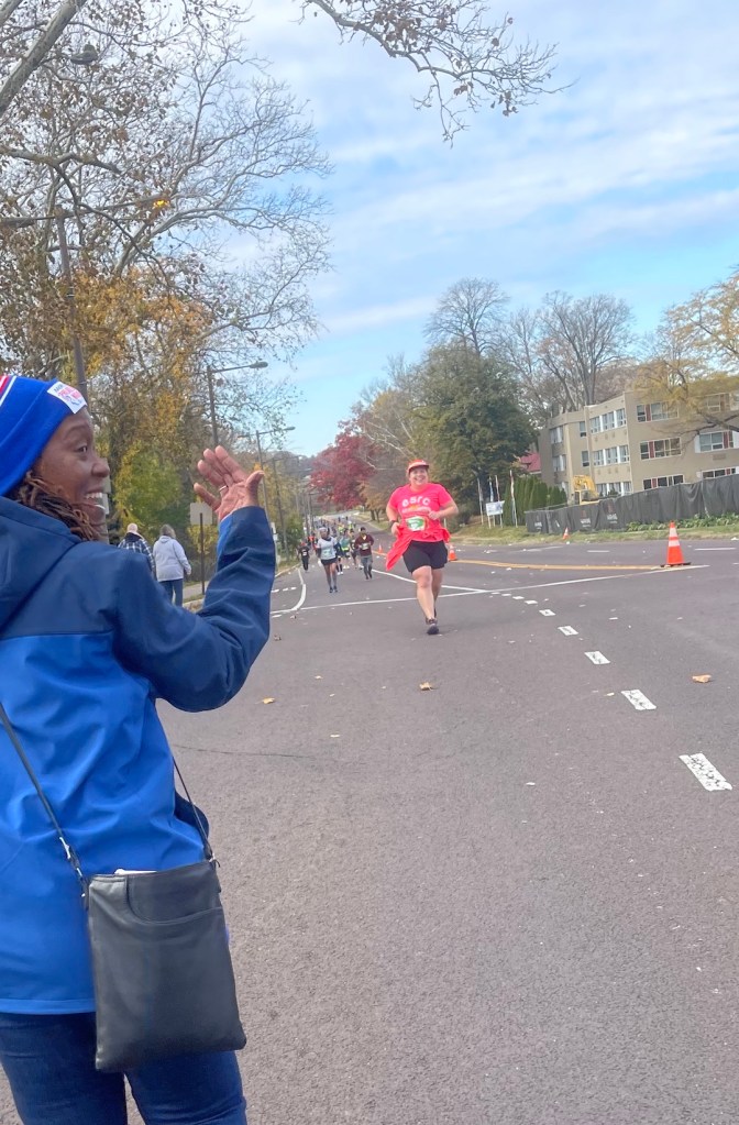 Vanessa Junkin running up hill with person cheering to the left.