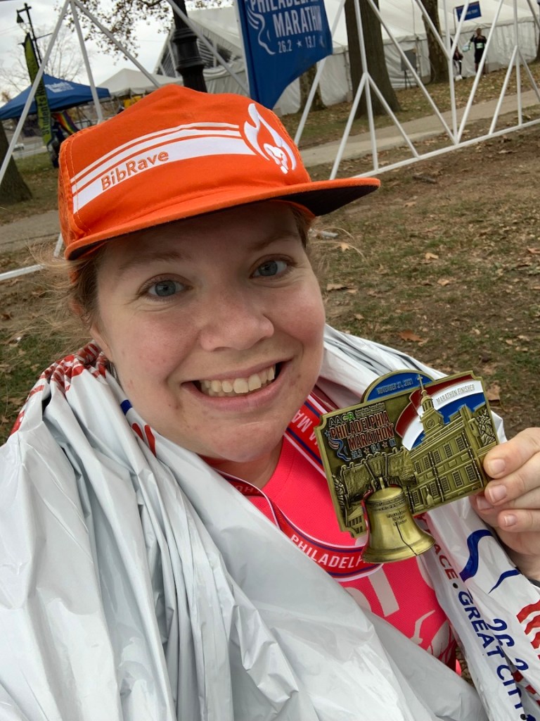 Vanessa Junkin takes selfie holding Philadelphia Marathon finisher medal.