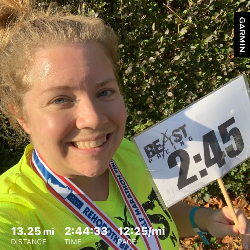 Vanessa Junkin takes a selfie with her 2:45 pace sign. Text reads "13.25 mi Distance" "2:44:33 Time" and "12:25/mi Pace." 