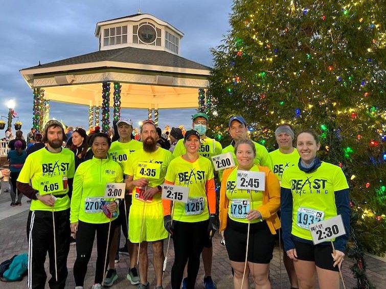 A group of pacers — runners wearing neon yellow shirts holding signs with numbers on them. 