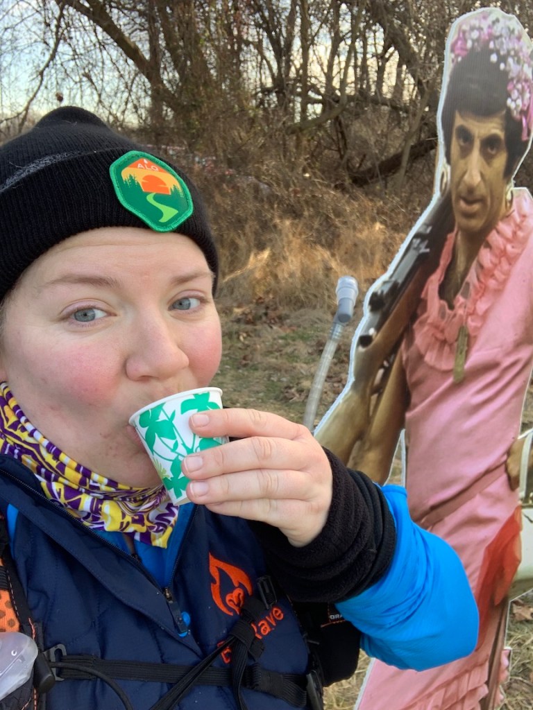Selfie of Vanessa Junkin sipping from small cup with M*A*S*H character cutout. 