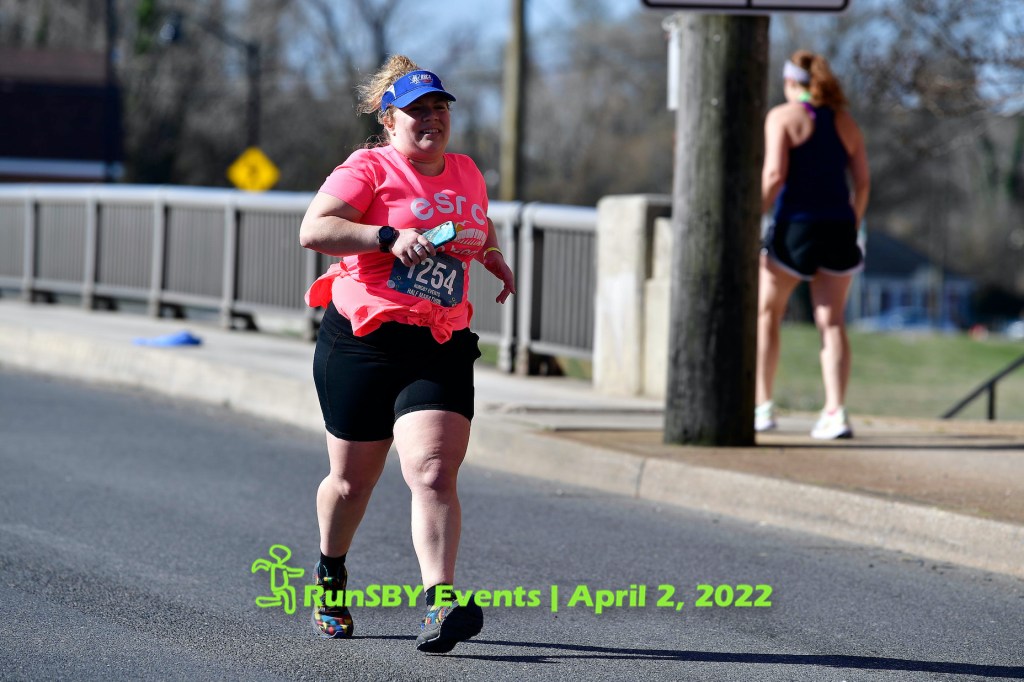 Female runner in pink shirt and black shorts running near the end of the Salisbury Half Marathon. 
