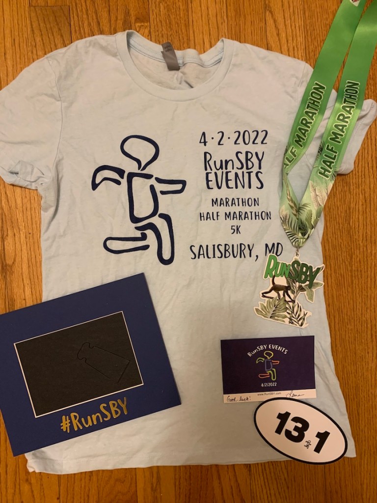 Race swag laid out — shirt, medal, picture frame, note, 13.1 sticker. 