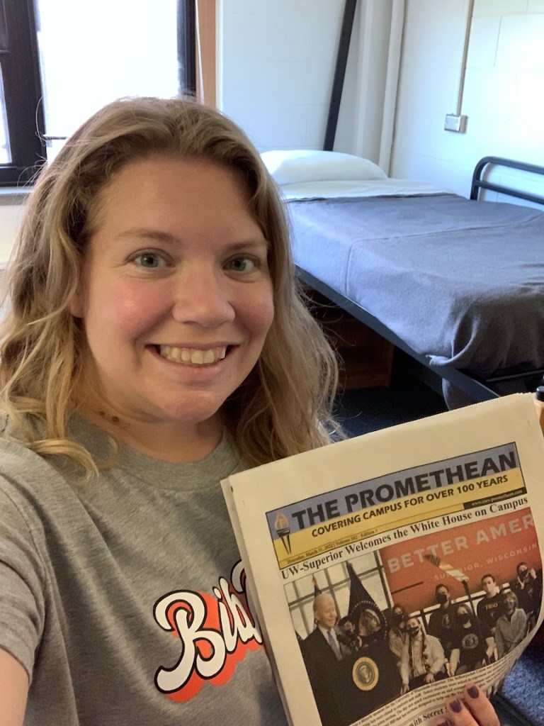 Selfie of Vanessa Junkin in college dorm room with college newspaper.