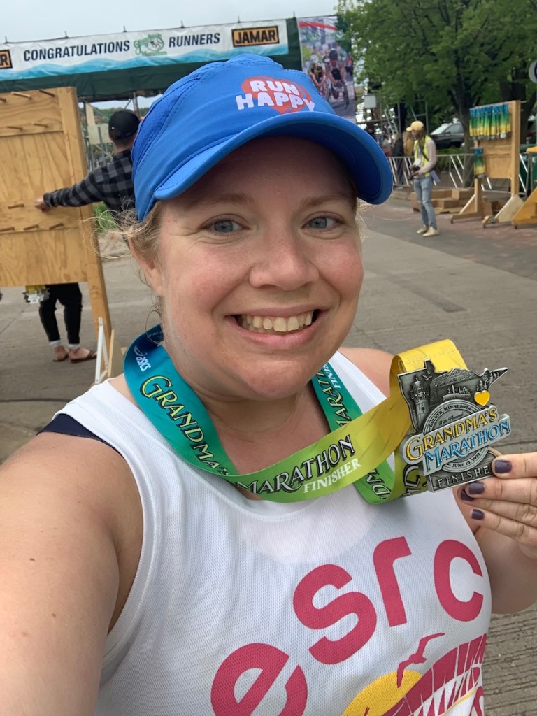 Selfie of Vanessa Junkin holding Grandma's Marathon finisher medal.