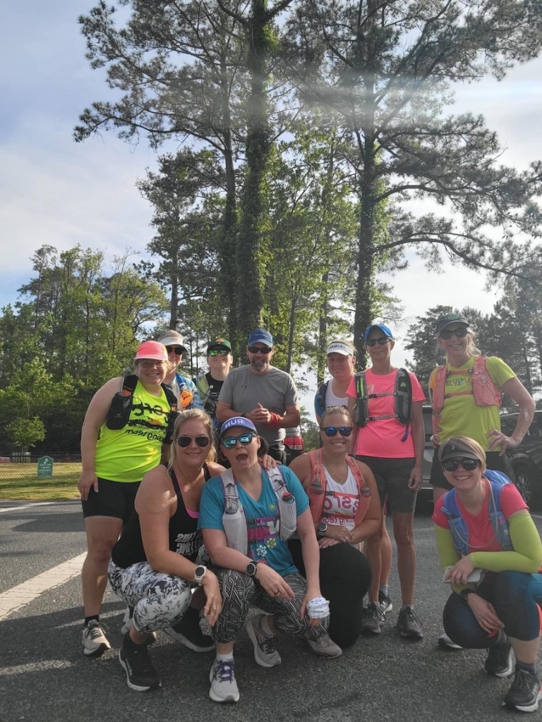 Group of runners poses for a photo with trees in the background. 