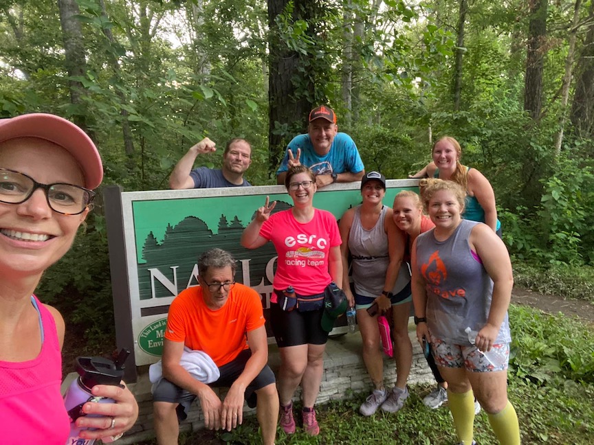 A group poses near the Naylor Mill Forest Trail sign. 