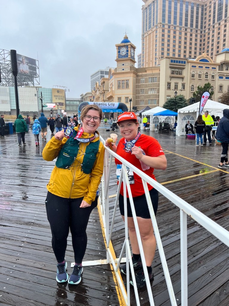 Two friends smiling and posing for a photo on the Atlantic City boardwalk after completing a race.