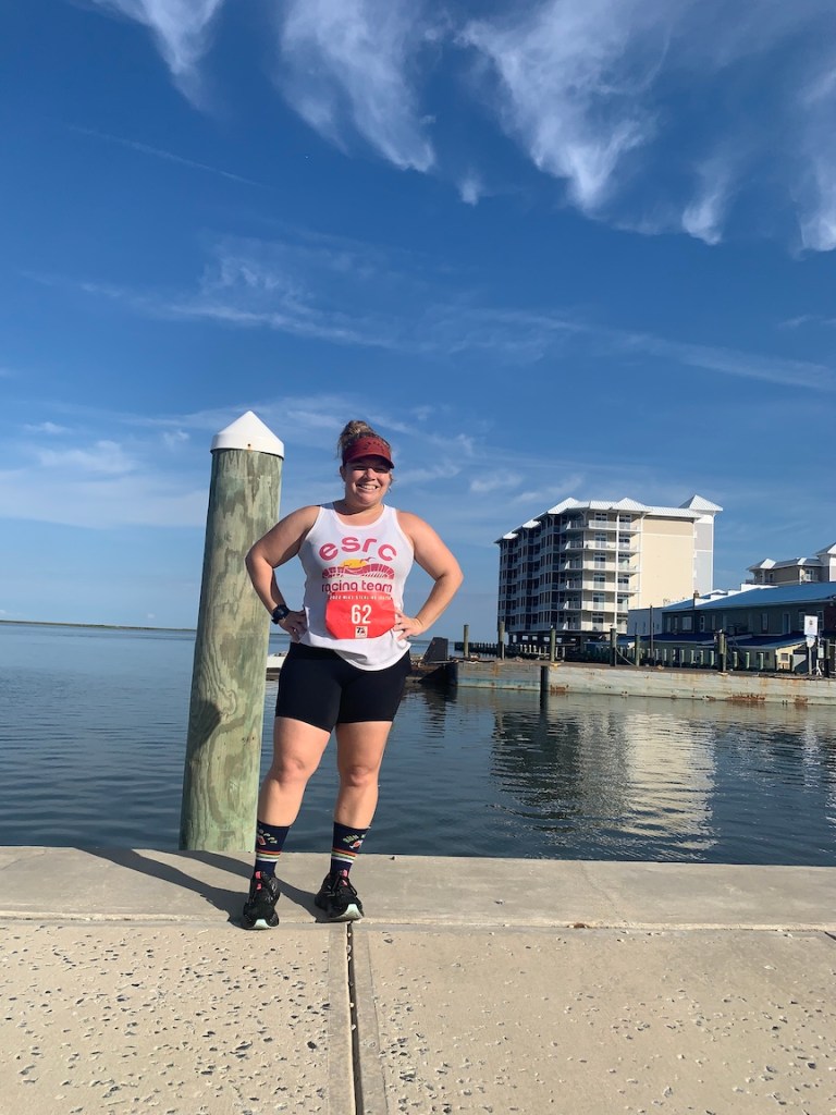 Vanessa Junkin poses in running clothes for a photo on the Crisfield City Dock, with water in the background. 