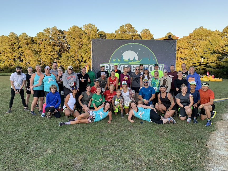 Large group of runners poses in front of large Pemberton 24 sign.