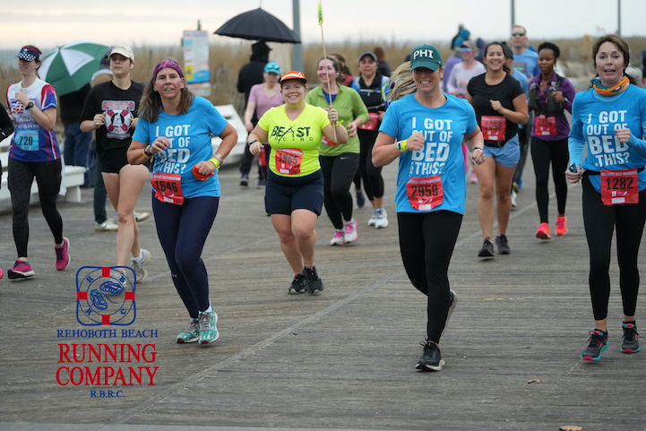 Vanessa Junkin smiles as she paces, wearing a neon yellow shirt and dark shorts, with other runners surrounding her. 