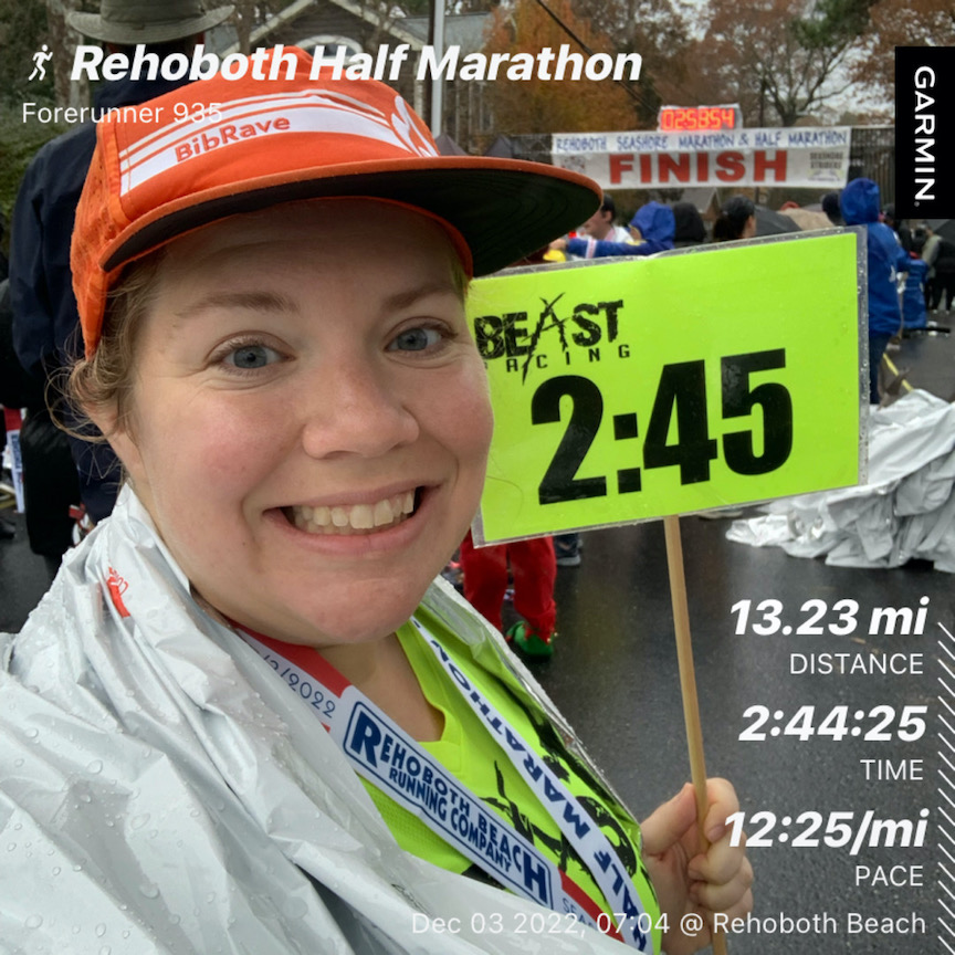 Selfie of Vanessa Junkin smiling with 2:45 pace sign and text that reads "13.21 mi distance," "2:44:25 time" and "12:25/mi pace." 
