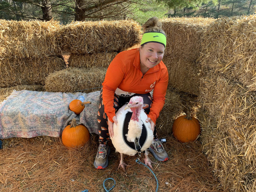 Vanessa Junkin poses with a turkey, surrounded by hay bales. 