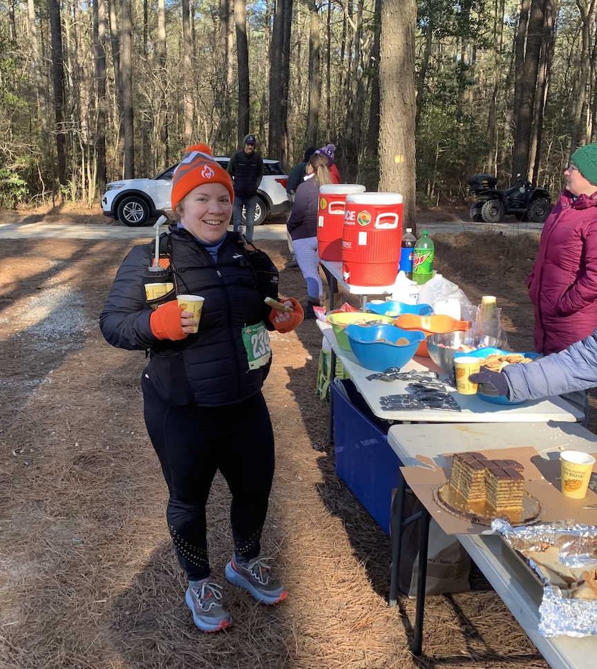 Bundled-up female runner stopped at aid station and smiling. 