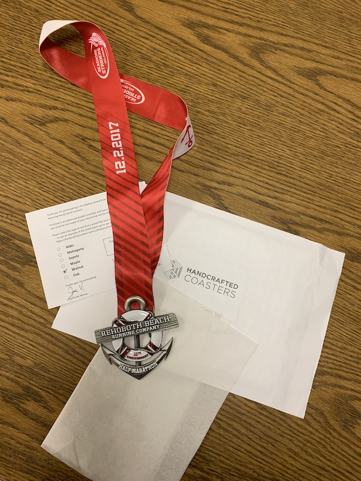 Photo of medal with ribbon, a check box paper with "walnut" checked, and a padded envelope with "Handcrafted Coasters" on it.