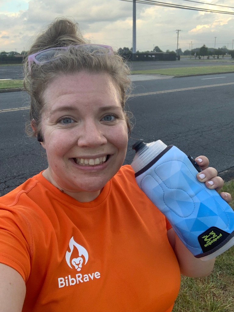 Selfie of Vanessa Junkin in orange BibRave shirt holding Amphipod Hydraform Chillder bottle. 
