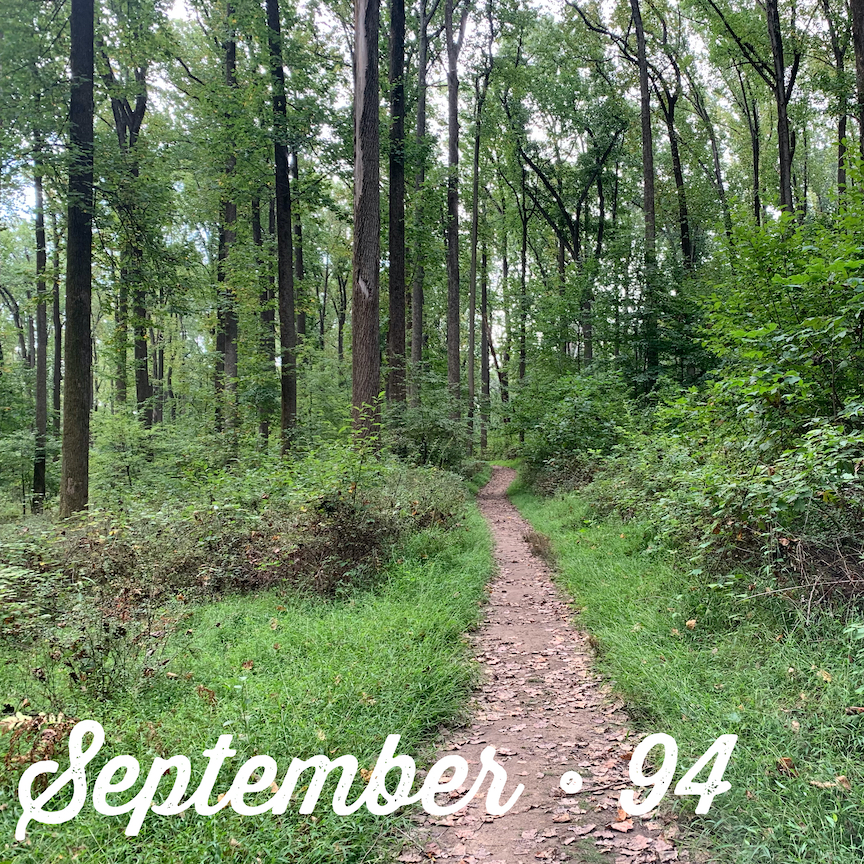 View of a thin trail through the woods with the text "September - 94" in script.