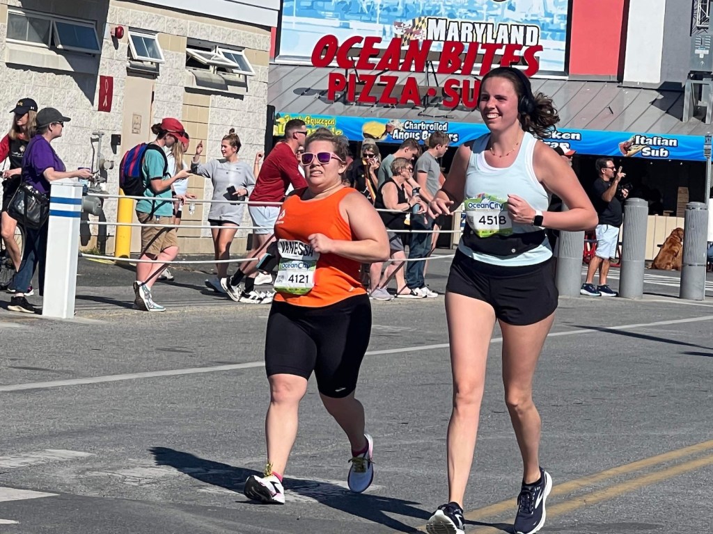 Vanessa makes a struggling expression as she is running. A taller female runner is next to her. 