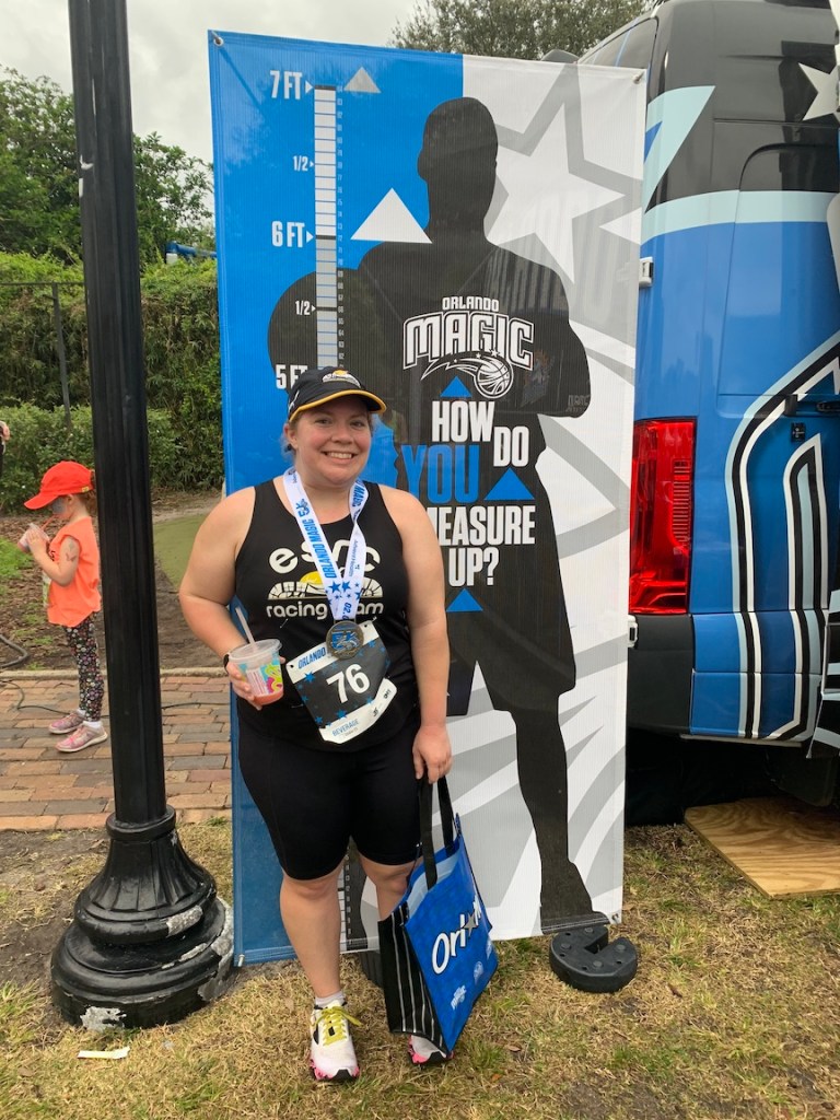Vanessa Junkin, 5 feet, stands next to an Orlando Magic "How Do You Measure Up?" banner, with the basketball player silhouette at 7 feet.