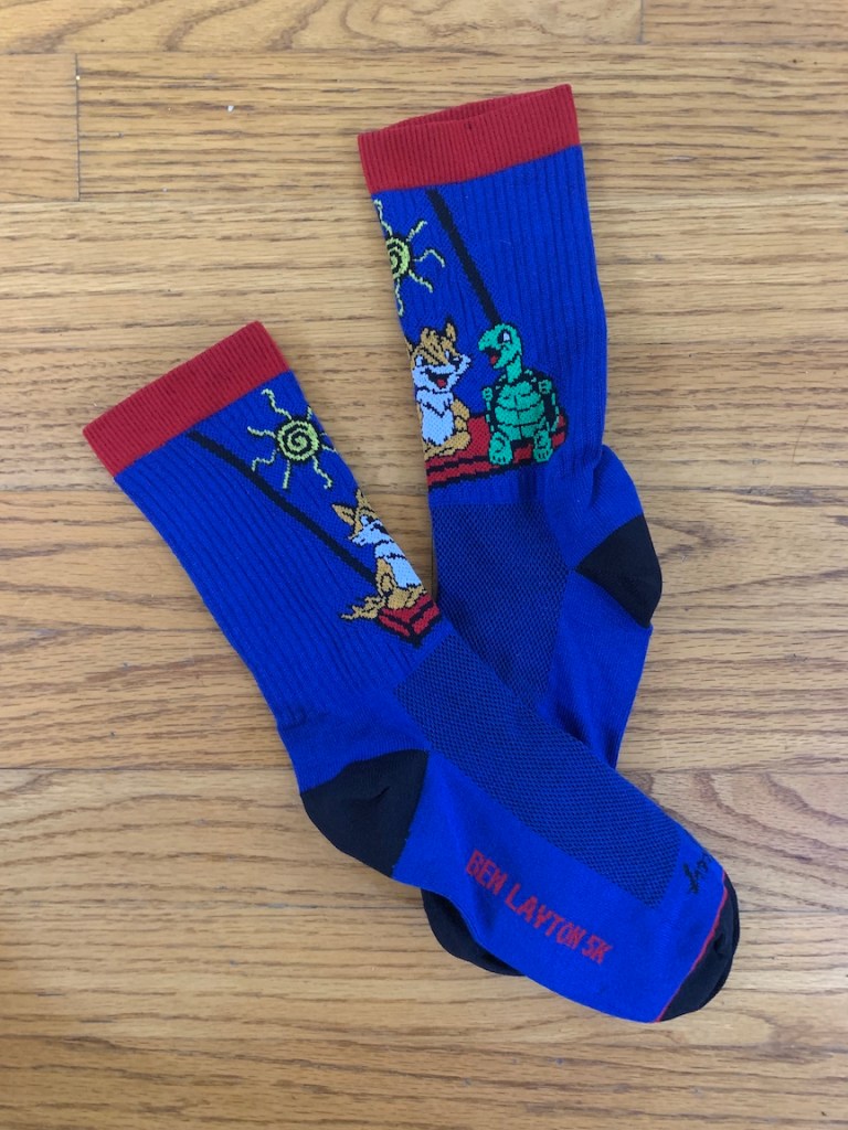 Custom blue socks with red trim and animals on a swing on a wood floor background.