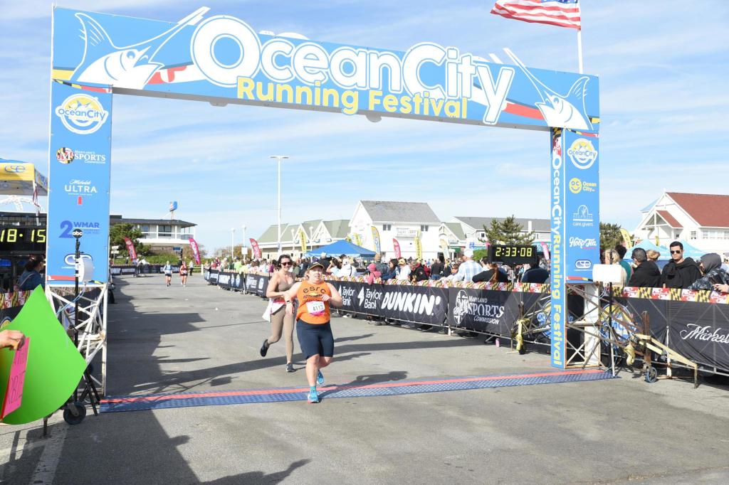 Vanessa Junkin crosses the finish line of the Ocean City Half Marathon under an arch that says Ocean City Running Festival. 