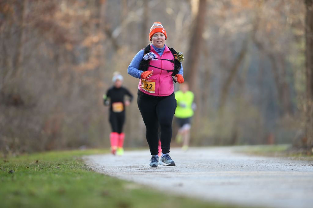 Vanessa Junkin runs on the NCR Trail, with blurred runners in the background. 