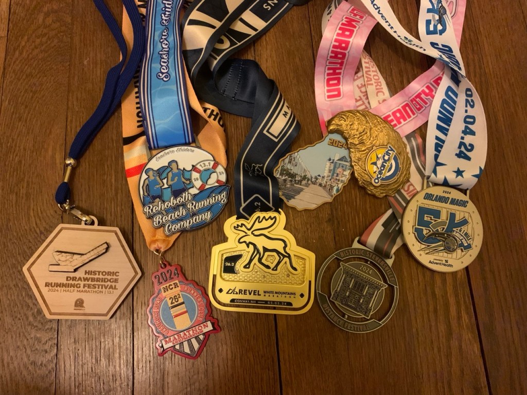 Group of seven race medals on a wooden floor.