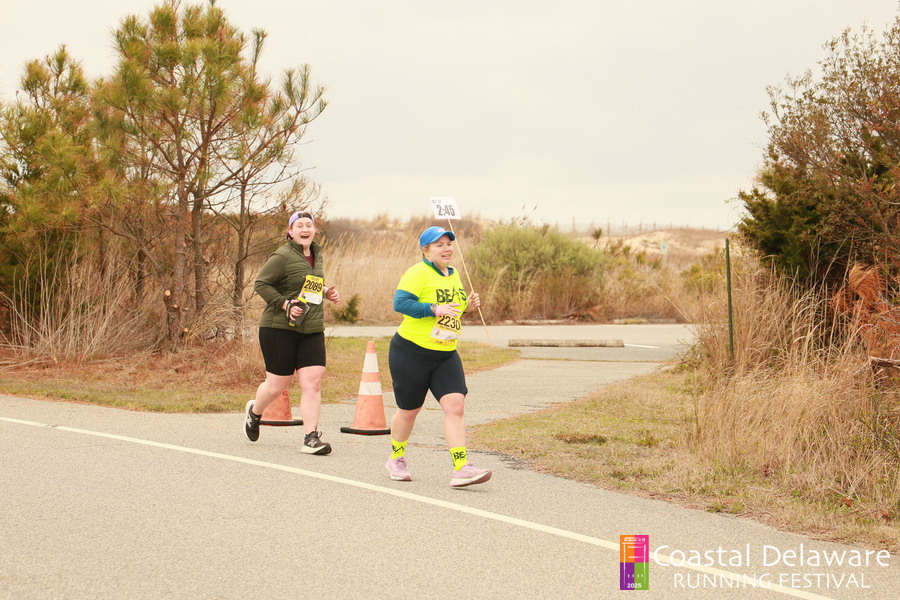 Vanessa Junkin pacing a race, holding a 2:45 sign, with a runner behind her.