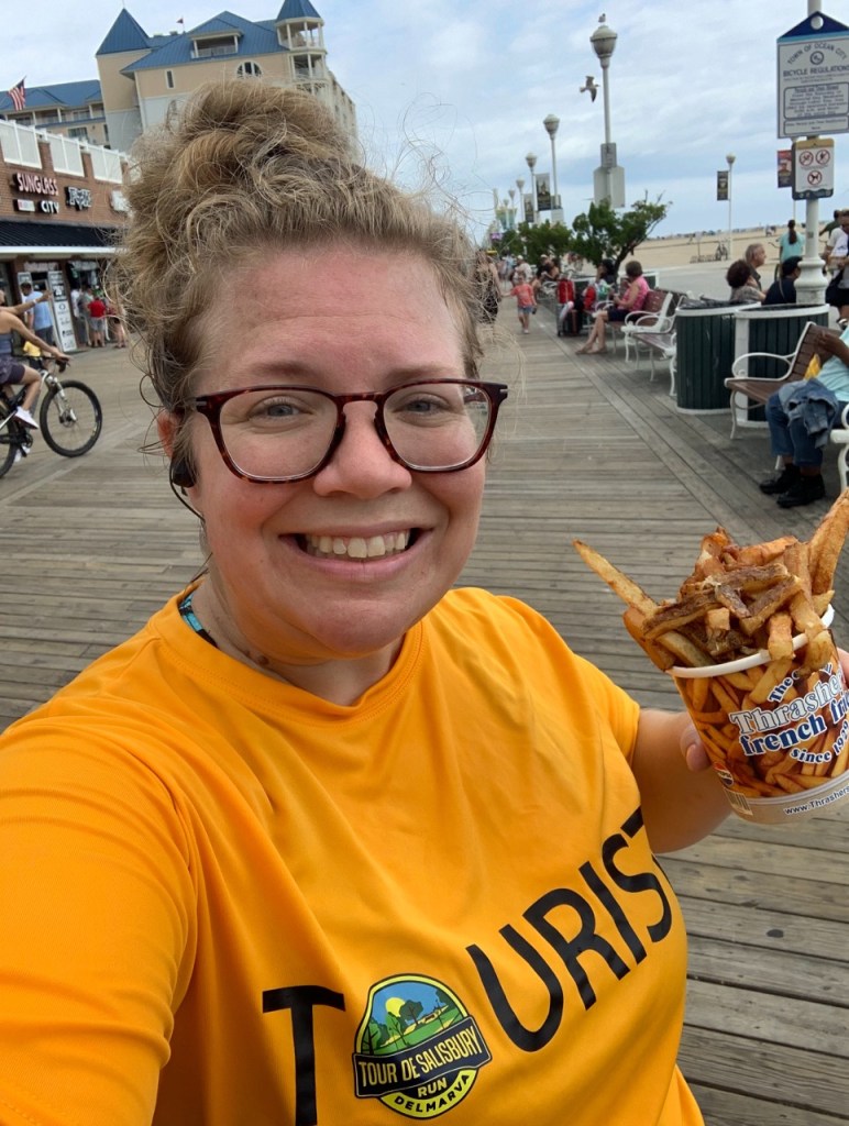 Selfie of female runner on the Ocean City Boardwalk, holding a cup of fries.